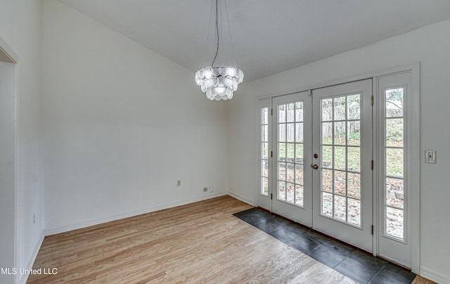 doorway with hardwood / wood-style floors, french doors, a wealth of natural light, and a notable chandelier