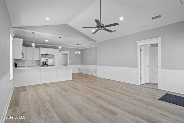 unfurnished living room with light wood-type flooring, ceiling fan, and vaulted ceiling