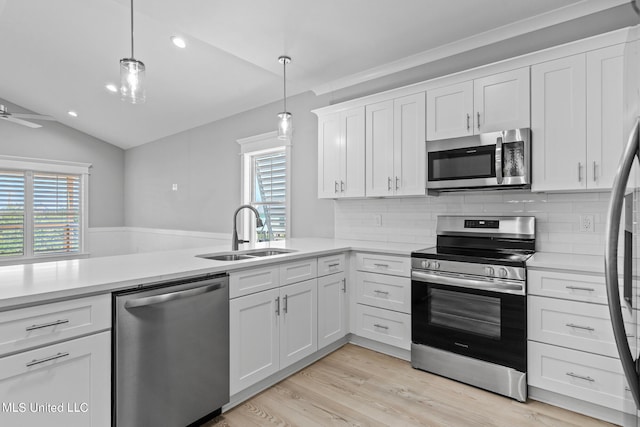 kitchen with white cabinetry, stainless steel appliances, hanging light fixtures, and sink