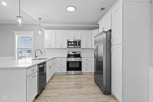 kitchen with stainless steel appliances, pendant lighting, sink, white cabinets, and light hardwood / wood-style flooring