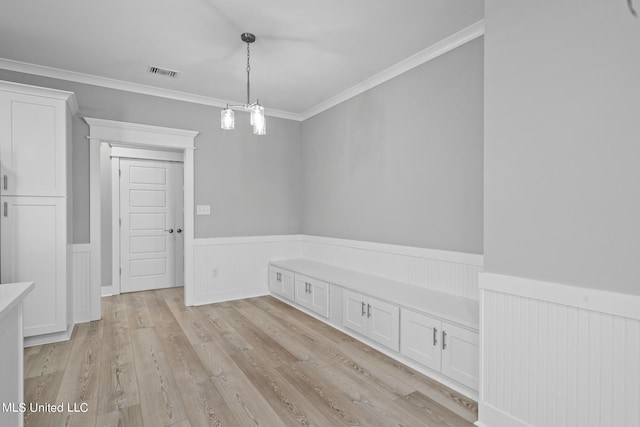 unfurnished dining area featuring light hardwood / wood-style flooring, crown molding, and an inviting chandelier