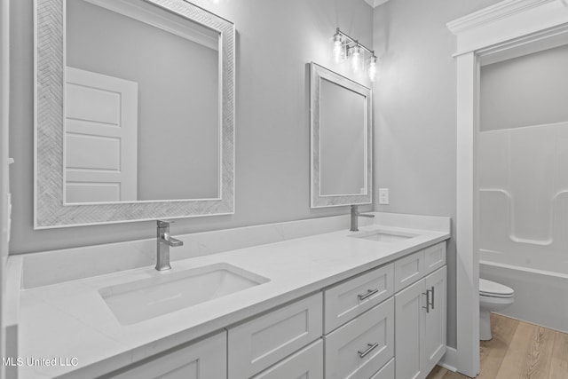 full bathroom featuring toilet, vanity, hardwood / wood-style flooring, and  shower combination