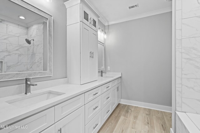 bathroom featuring hardwood / wood-style floors, vanity, tiled shower, and crown molding