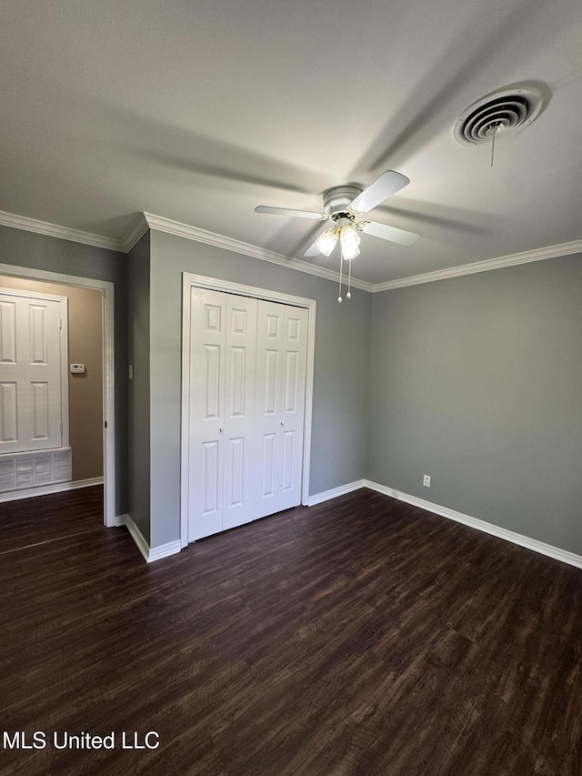 unfurnished bedroom with visible vents, crown molding, baseboards, a closet, and dark wood-style floors