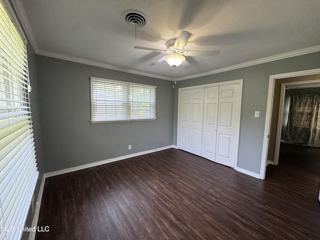 unfurnished bedroom featuring crown molding, dark wood-style flooring, ceiling fan, baseboards, and a closet