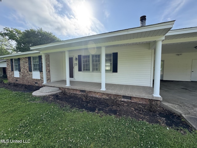 view of front of home with a porch, a front yard, crawl space, a carport, and driveway
