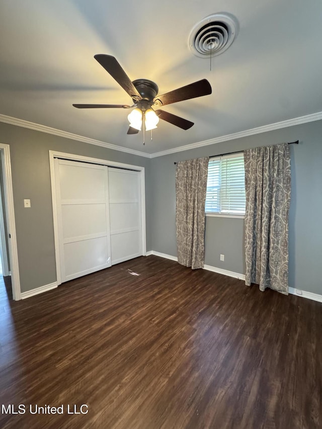 unfurnished bedroom featuring visible vents, ornamental molding, a closet, wood finished floors, and baseboards