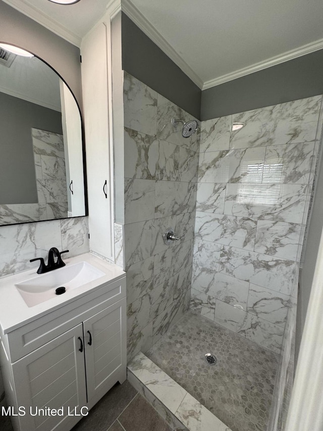 bathroom with visible vents, a tile shower, ornamental molding, and vanity