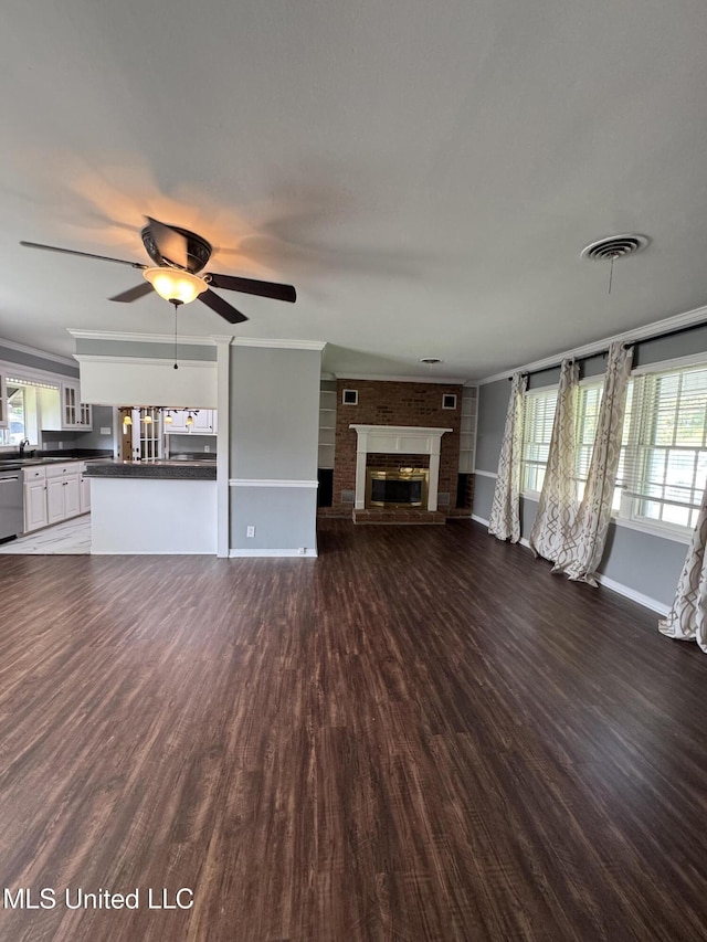 unfurnished living room featuring baseboards, a ceiling fan, a glass covered fireplace, and dark wood-style floors
