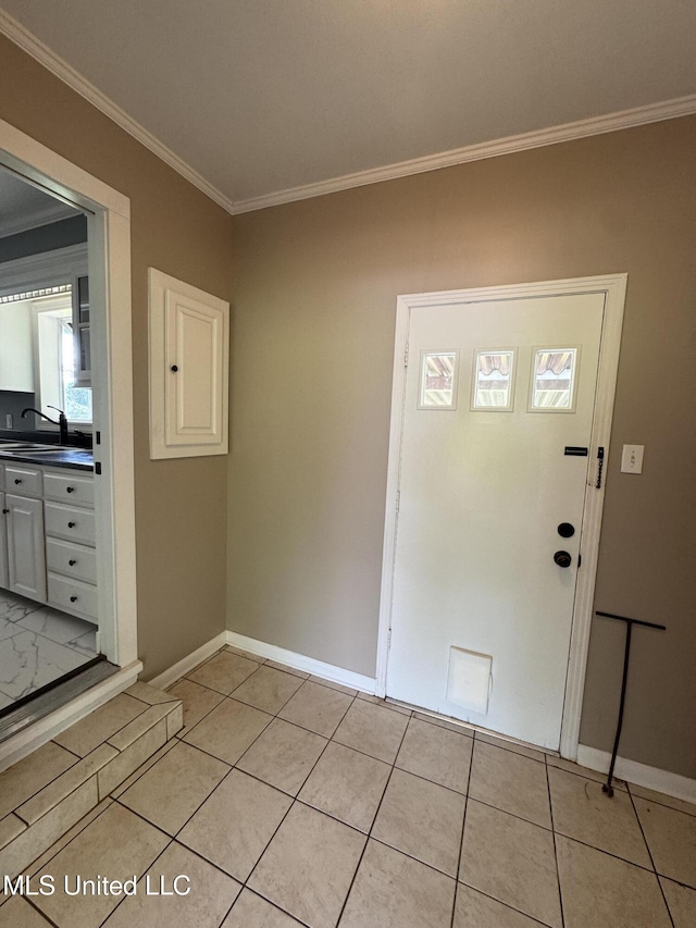 entryway with crown molding, baseboards, and light tile patterned floors