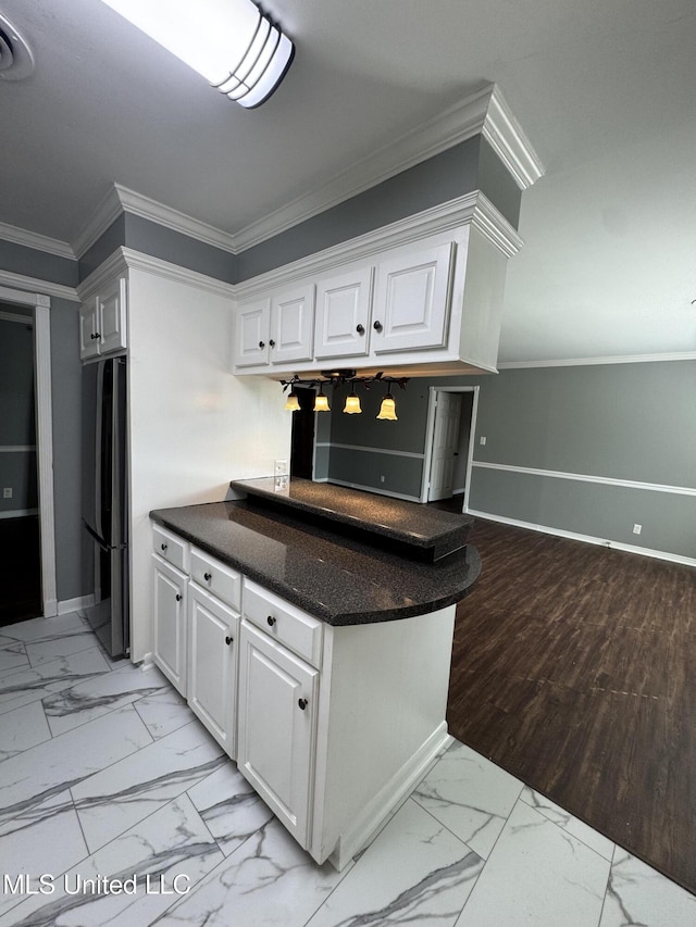 kitchen featuring freestanding refrigerator, marble finish floor, ornamental molding, baseboards, and white cabinets