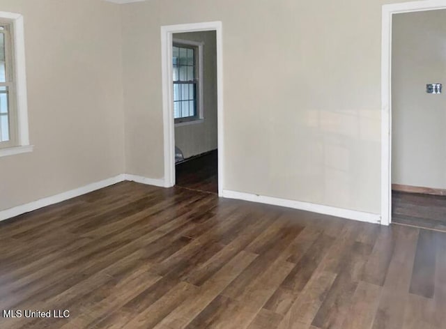 unfurnished room featuring dark wood-type flooring and a wealth of natural light