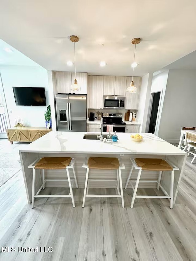 1302 Magnolia St Unit 202, Gulfport, MS 39507 - kitchen featuring appliances with stainless steel finishes, light wood finished floors, light countertops, and a large island