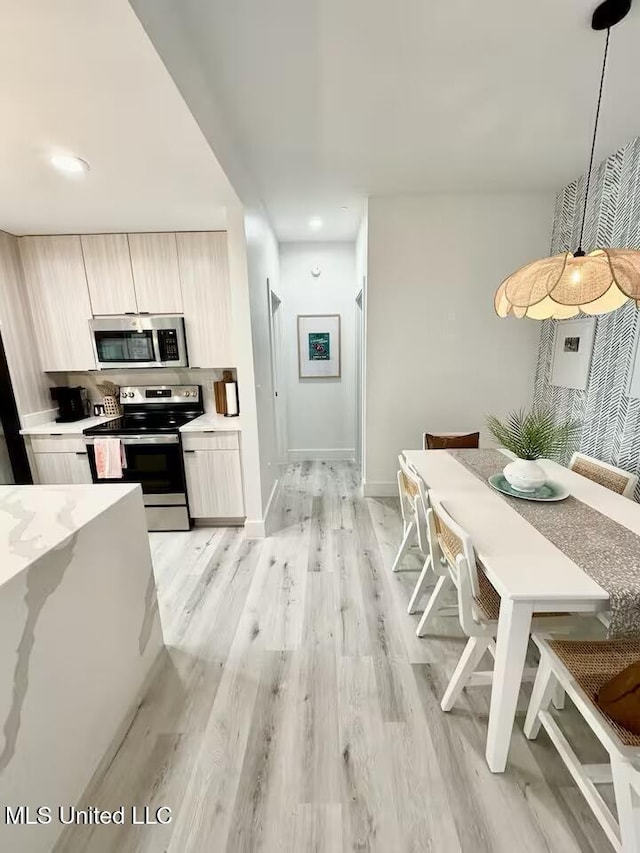 1302 Magnolia St Unit 202, Gulfport, MS 39507 - kitchen featuring appliances with stainless steel finishes, modern cabinets, light countertops, light wood-style flooring, and pendant lighting