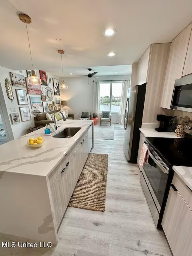 1302 Magnolia St Unit 202, Gulfport, MS 39507 - kitchen featuring appliances with stainless steel finishes, modern cabinets, light stone countertops, an island with sink, and a ceiling fan