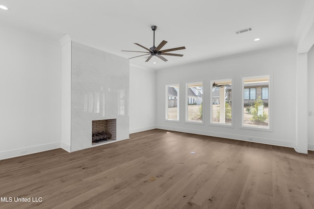 unfurnished living room featuring a tile fireplace, visible vents, crown molding, and ceiling fan