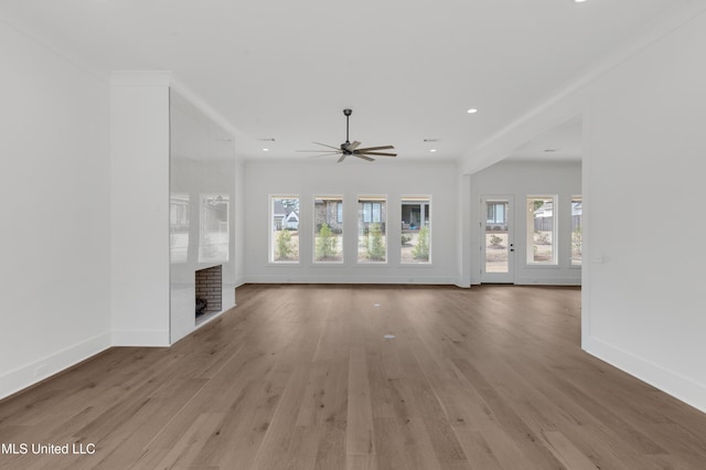 unfurnished living room with light wood-type flooring, crown molding, baseboards, and recessed lighting