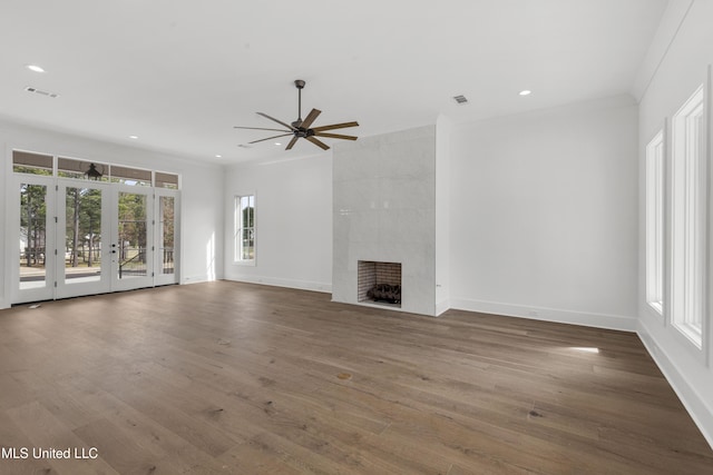 unfurnished living room featuring visible vents, a tiled fireplace, and wood finished floors