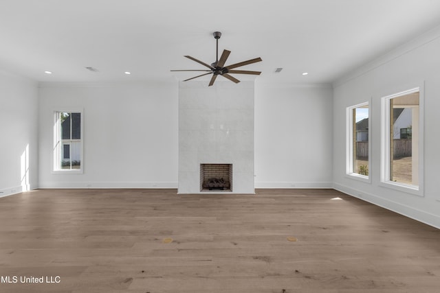 unfurnished living room featuring ornamental molding, a tile fireplace, baseboards, and light wood finished floors