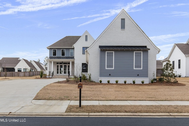 view of front of home with a standing seam roof, a porch, metal roof, and brick siding