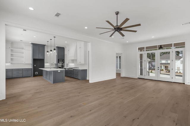 kitchen featuring a kitchen island, open floor plan, light countertops, appliances with stainless steel finishes, and decorative light fixtures