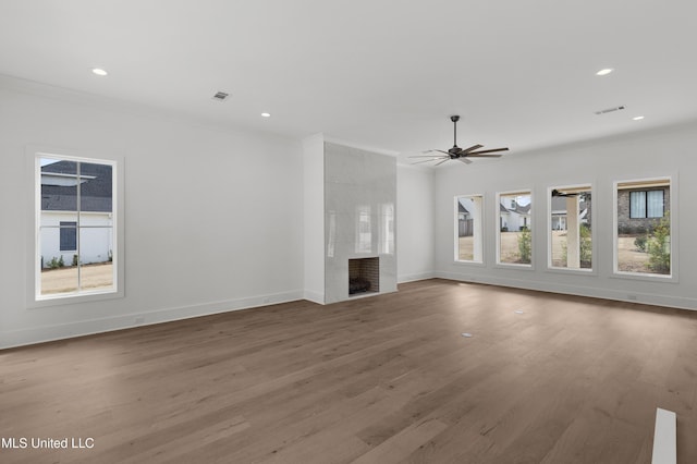 unfurnished living room with baseboards, wood finished floors, a tile fireplace, and crown molding