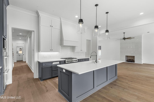 kitchen with decorative light fixtures, gray cabinets, light countertops, white cabinetry, and a sink