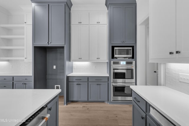 kitchen featuring tasteful backsplash, light wood-style flooring, appliances with stainless steel finishes, gray cabinets, and light countertops