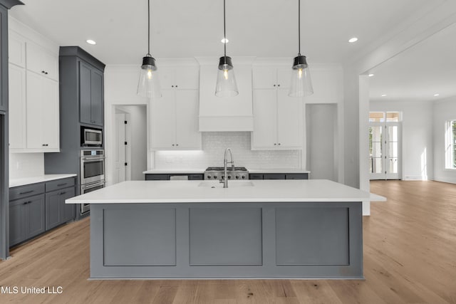 kitchen with light countertops, a center island with sink, and decorative light fixtures