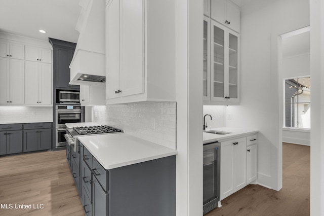 kitchen featuring white cabinets, wine cooler, glass insert cabinets, custom exhaust hood, and light countertops