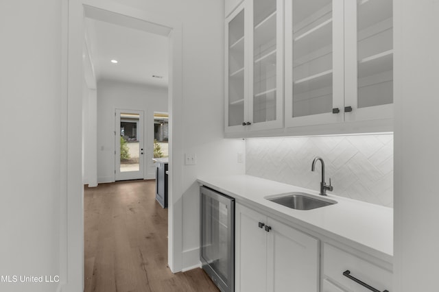 interior space with beverage cooler, baseboards, dark wood-type flooring, a sink, and backsplash