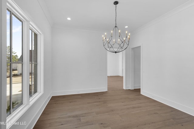 unfurnished dining area with dark wood-style floors, ornamental molding, baseboards, and an inviting chandelier