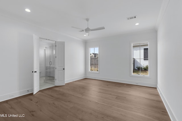 unfurnished bedroom featuring light wood-style flooring, multiple windows, visible vents, and crown molding