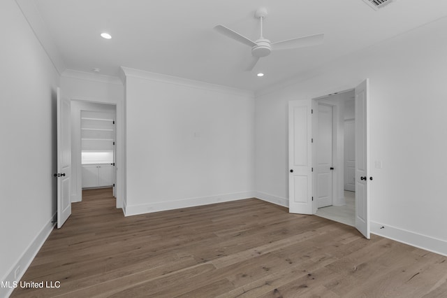 unfurnished bedroom featuring baseboards, recessed lighting, wood finished floors, and crown molding