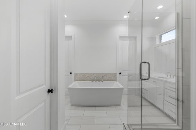 full bathroom with recessed lighting, a soaking tub, vanity, and tile walls