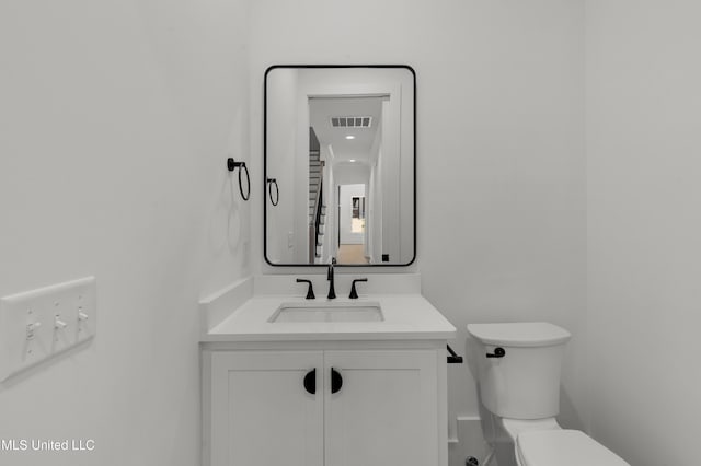 half bathroom with toilet, visible vents, and vanity