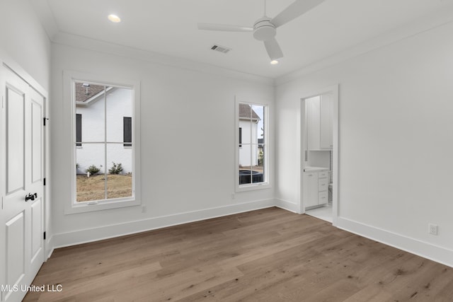 unfurnished bedroom with light wood-type flooring, multiple windows, visible vents, and crown molding