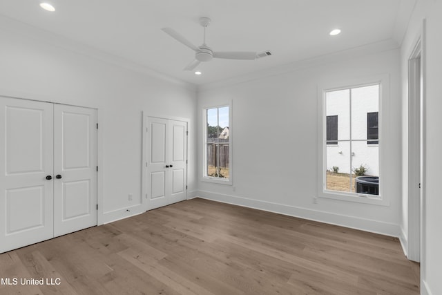 unfurnished bedroom featuring crown molding, light wood finished floors, multiple closets, recessed lighting, and baseboards