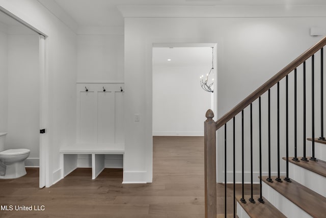 mudroom featuring baseboards, crown molding, wood finished floors, and a notable chandelier