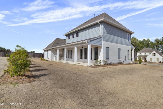 rear view of property with a patio, brick siding, a lawn, and fence