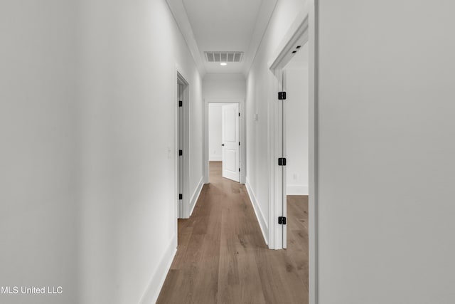 hallway featuring light wood-style flooring, visible vents, and baseboards