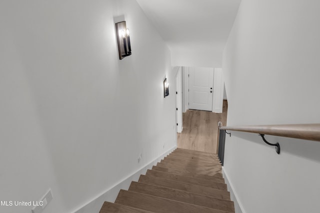 stairway with wood finished floors and baseboards