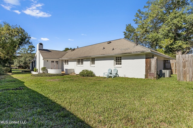 rear view of property with central AC and a lawn