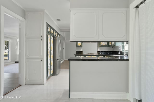 kitchen featuring sink, light tile patterned floors, stainless steel fridge, crown molding, and white cabinets