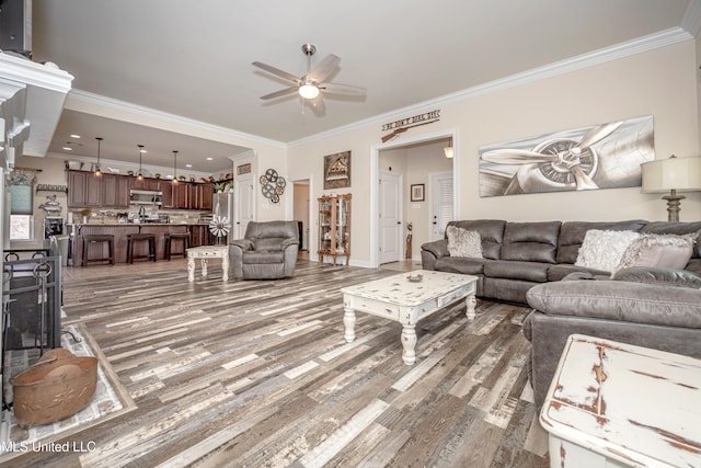 living room featuring dark wood-type flooring, ceiling fan, and crown molding