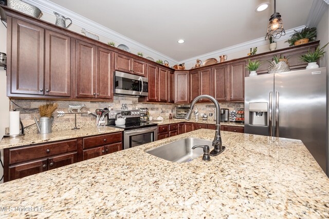 kitchen featuring sink, ornamental molding, decorative light fixtures, light stone counters, and stainless steel appliances