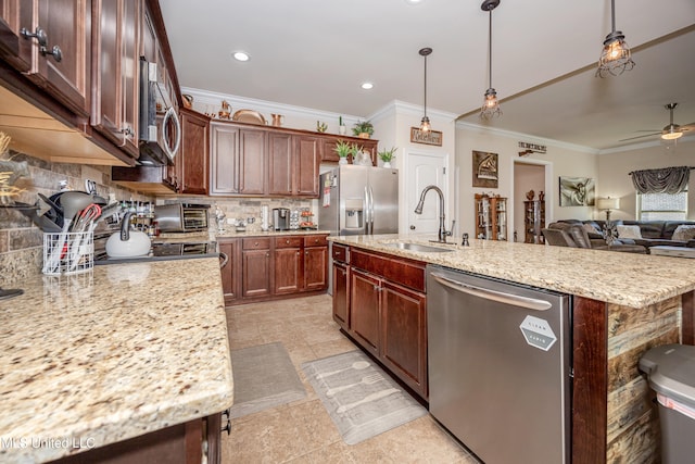 kitchen featuring a center island with sink, sink, ceiling fan, appliances with stainless steel finishes, and decorative light fixtures