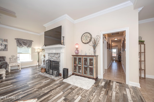 living room featuring hardwood / wood-style flooring, crown molding, and a brick fireplace