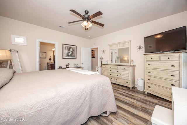 bedroom with ceiling fan, dark wood-type flooring, and ensuite bath