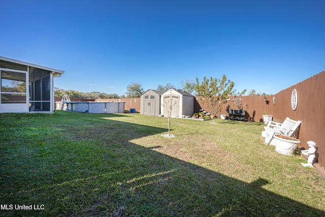 view of yard with a fenced in pool, a sunroom, and a storage shed